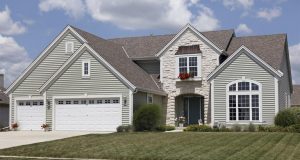Suburban home with a green lawn and grey siding 